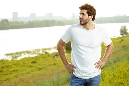 Handsome young man standing on a green lawn over urban background.の写真素材