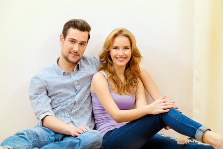 Happy couple sitting together on a floor at home. Moving to a new home. Apartment repair.