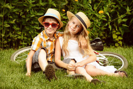 Happy summer holidays. Two happy children on a green lawn at a summer park.の写真素材
