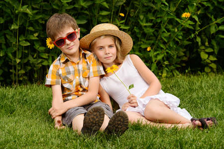 Happy summer holidays. Two happy children on a green lawn at a summer park.の写真素材