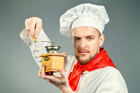 Portrait of a male chef cook in uniform holding coffee grinder. Coffee concept. Occupation. Studio shot.の写真素材