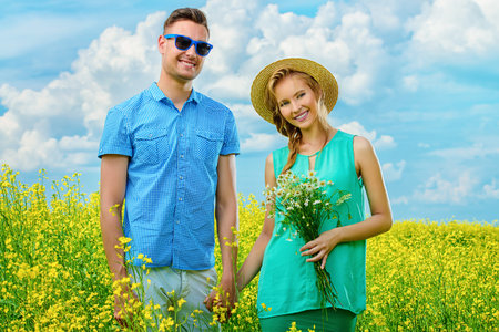 Happy young people in love on a meadow on a sunny summer day. Summer holidays. Love concept.