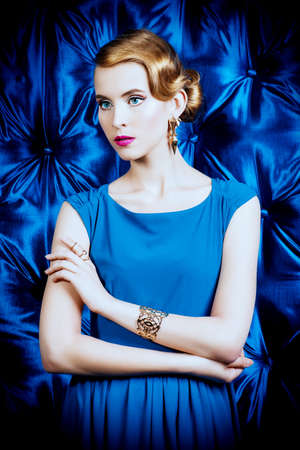 Gorgeous young woman in elegant evening dress standing by a vintage wallpaper. Fashion shot. Retro hairstyle.の写真素材