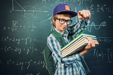 Education, high school, college. Portrait of a student boy standing by a school blackboard.