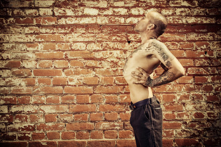 Experienced yoga man doing various yoga poses outdoor by the brick wall. Yoga concept.