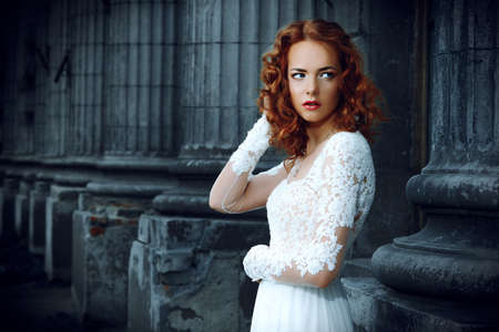 Beautiful fashion model in luxurious white dress on a city street. Charming bride woman walking down the street. Beauty, fashion.の写真素材