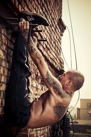 Experienced yoga man doing various yoga poses outdoor by the brick wall. Yoga concept.