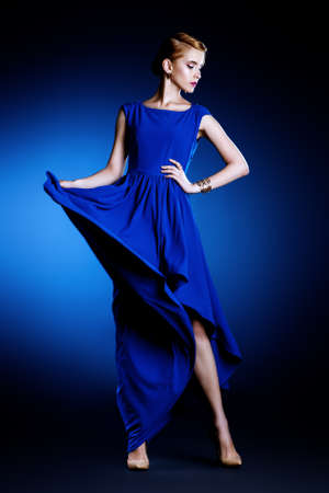 Fashion portrait of a beautiful young woman in  elegant evening dress posing in motion at studio. Hairstyle.の写真素材