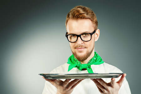 Portrait of a male chef cook in uniform holding empty tray. Copy space. Occupation. Studio shot.の写真素材