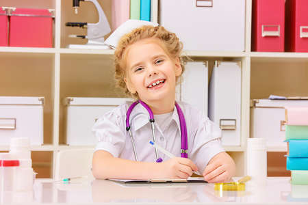 Pretty little girl playing a doctor at home. Different occupations. Children's Health, Pediatrics.の写真素材
