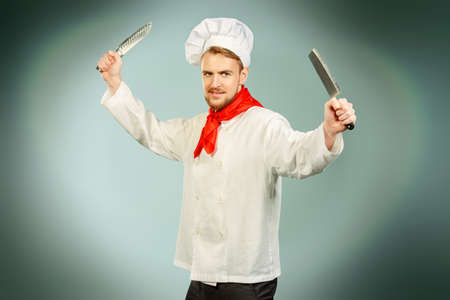 Portrait of a professional male cook holding knifes. Occupation. Studio shot.の写真素材