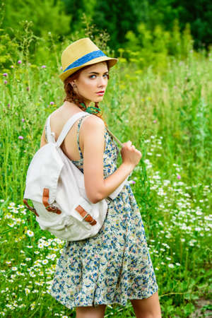 Romantic girl standing on a yellow meadow on a sunny summer day. Smiling young woman outdoor. Holidays, summer vacation.の写真素材
