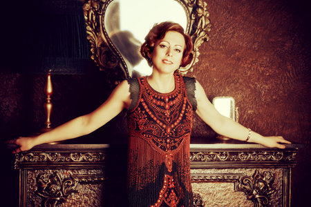 Portrait of a beautiful mature woman in evening dress standing in a room with classic style...