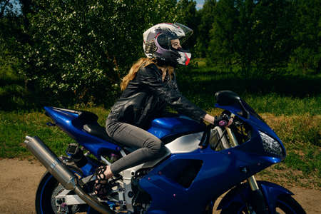 Sexy girl motorcyclist wearing a helmet rides on her motorcycle on the highway. The spirit of freedom and independence. Adventure.の写真素材