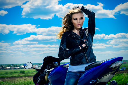 Sexy young woman biker sitting on her motorcycle on a road. Beauty, fashion. Adventure concept.の写真素材
