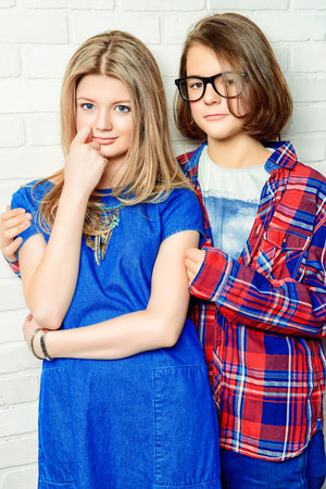 Two modern teenage boy and girl standing together by a brick wall. Friendship. First love.の写真素材