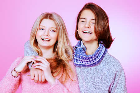 Portrait of happy teenage boy and girl standing together over pink background. Friendship. First love.の写真素材