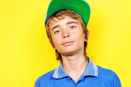 Portrait of a smiling teenage boy over yellow background. Studio shot. Teen fashion.の写真素材