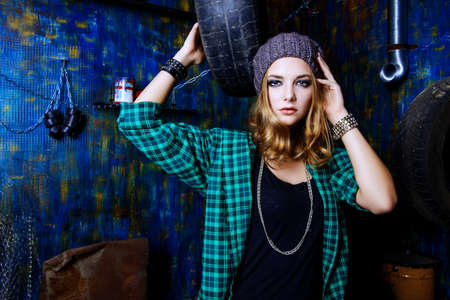 Portrait of a modern teenager girl wearing street clothes sitting in the old garage. Grunge style.の写真素材