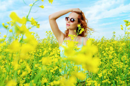 Happy smiling girl at a yellow meadow on a sunny summer day. Smiling young woman outdoor. Holidays, summer vacation.の写真素材