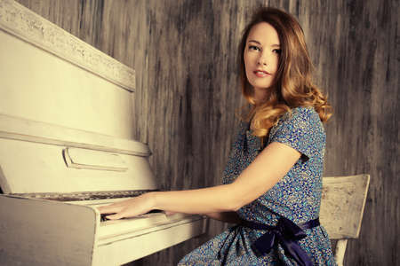Romantic young woman playing the piano. Music and art concept.の写真素材