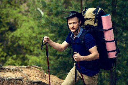 Adventure concept. Young man hiking in the forest. Active lifestyle, tourism. Tourist equipment.