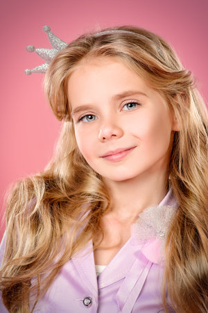 Portrait of a pretty little girl with beautiful blonde hair over pink background. Little princess...