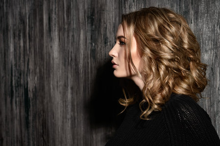 Profile portrait of blonde teenage girl standing by a grunge wall. Generation. Youth style, fashion.