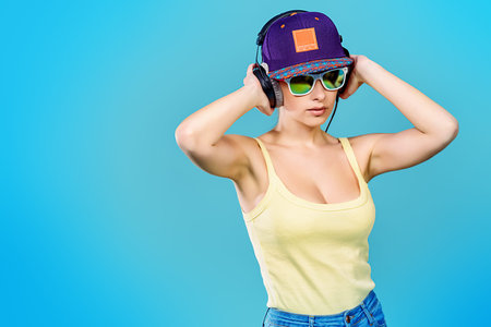 Modern young woman enjoys listening to music in headphones. Positive emotions, leisure. Copy space.