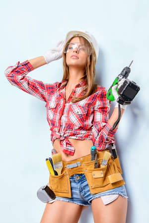 Attractive young woman doing repairs at home. Portrait of a female construction worker. Building, repair concept.の写真素材