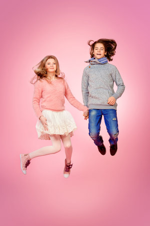Two happy teenage boy and girl jumping together over pink background. Friendship. First love.の写真素材