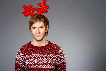 Portrait of a smiling young man in Christmas deer horns. Christmas party.の写真素材