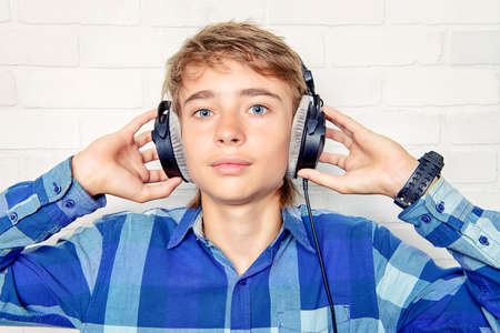 Modern teenage boy enjoys the music in headphones. Studio shot. Youth culture.の写真素材