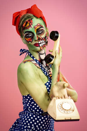 Portrait of a pin-up zombie woman over pink background. Body-painting project. Glamorous zombie girl. Halloween make-up.の写真素材