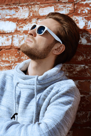 Young handsome man in casual clothes and sunglasses standing on a city street. Men's beauty,...