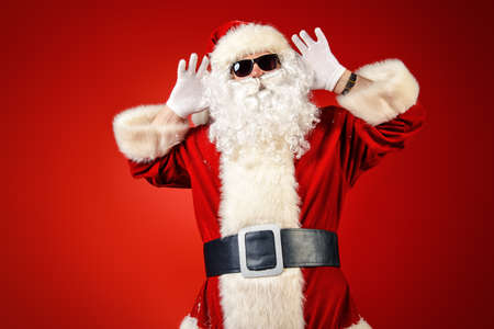Modern Santa Claus in sunglasses over Christmas red background.の写真素材
