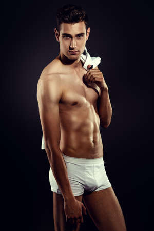 Portrait of a sexy young man in underwear. Studio shot over black background.の写真素材