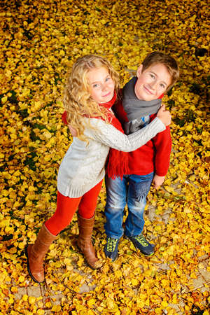 Two happy children in a beautiful autumn park. Children's fashion. Autumn leaf fall.の写真素材