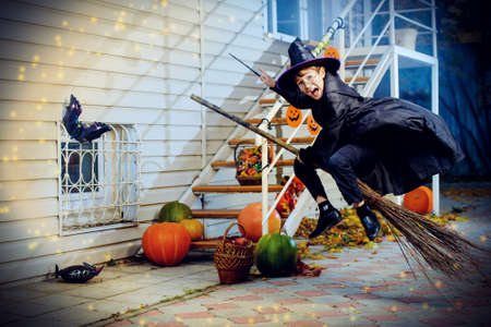 A boy in a costume of wizard flying on a broom with his magic wand. Trick or treat. Halloween celebration.の写真素材
