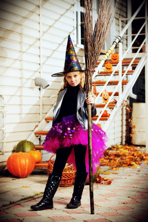 Pretty little girl in a costume of witch with her magic broom celebrating halloween. Trick or treat....