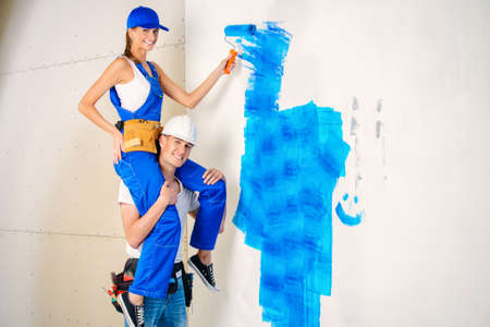 Happy young family painting walls in their new home. Repair, construction and mortgage concept.の写真素材