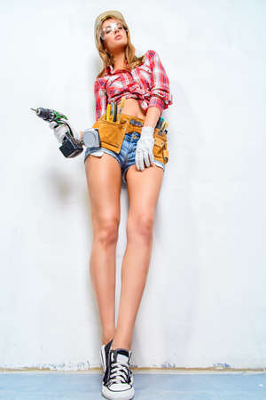 Sexy young woman doing repairs at home. Portrait of the attractive female construction worker. Building, repair concept.の写真素材