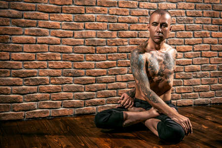 Mature man practicing yoga. Brick wall background. Healthy lifestyle. Meditation, concentration.の写真素材