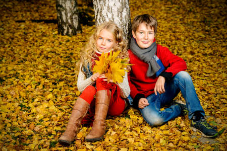 Two happy children in a beautiful autumn park. Children's fashion. Autumn leaf fall.の写真素材