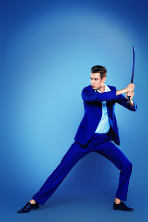 Businessman in a fighting stance with a sword in his hands. Struggle and competition concept.