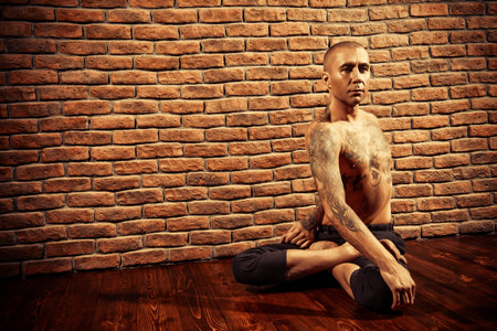 Mature man practicing yoga. Brick wall background. Healthy lifestyle. Meditation, concentration.の写真素材