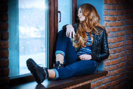 Dreamy teenage girl looking to the window. Youth style. Loft style interior.の写真素材