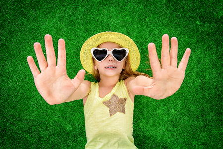Joyful little girl in colorful clothes and sunglasses lying on a green lawn. Kid's fashion. Summer...