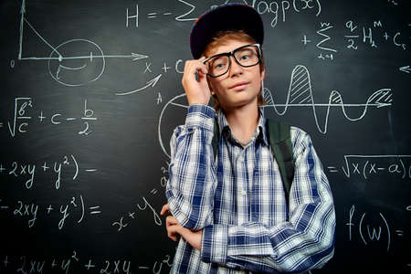 Education, high school, college. Portrait of a student boy standing by a school blackboard.の写真素材