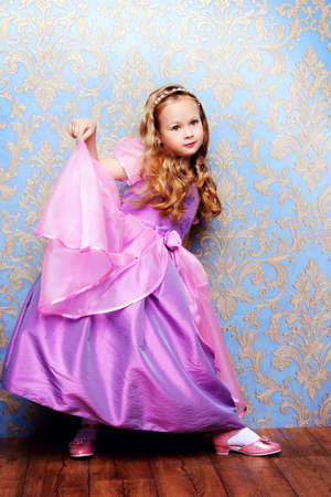 Pretty little girl in beautiful luxurious dress over vintage background. Kid's fashion.の写真素材